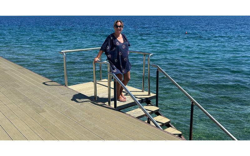 A tranquil moment on the deck overlooking the deep blue Mediterranean Sea and surrounding hills — one of the highlights of a spa retreat in Greece. Guest enjoying sea views from the sun deck at Thermae Sylla Spa in Evia, Greece