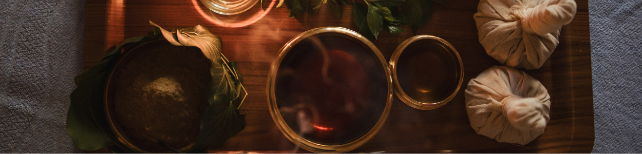 Ayurveda remedies Wooden tray with two china teapots, herbs and a candle