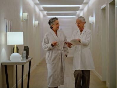 Mature woman in a white robe speaking with a female consultant at a menopause retreat