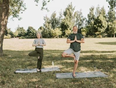 Mature man and woman practising yoga poses outdoors in nature at an anti-ageing and longevity retreat