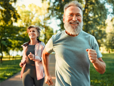 Smiling couple jogging in a leafy area in the sunshine