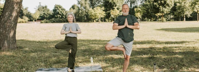 Mature man and woman practising yoga poses outdoors in nature at an anti-ageing and longevity retreat