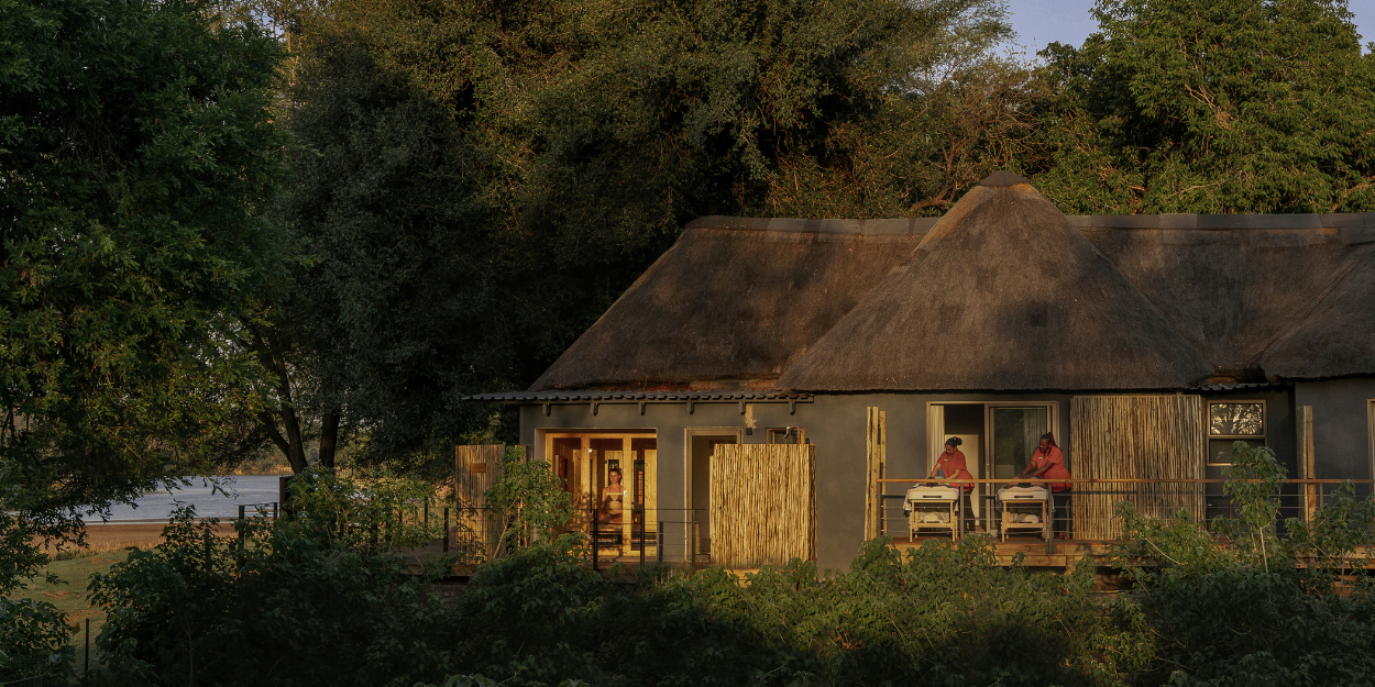 Wooden hut-style buildings showcasing open-air spa treatment rooms surrounded by greenery