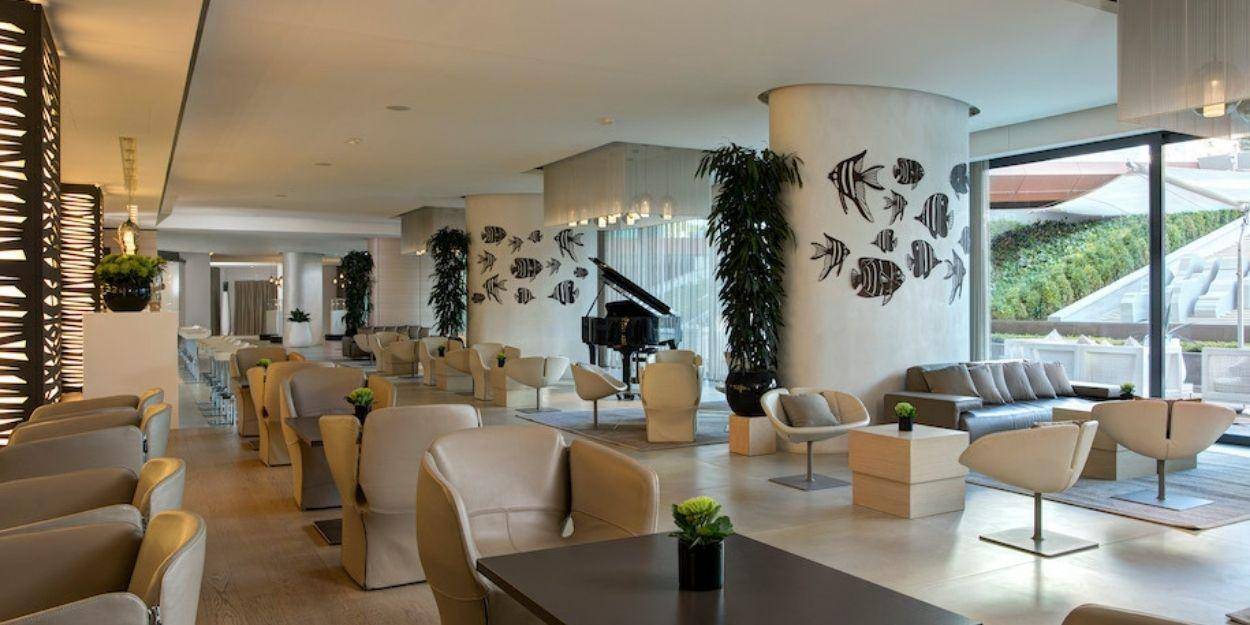 Airy lobby with pillars adorned with sculptures of fish shoals, leather neutral armchairs, and glossy dark tables