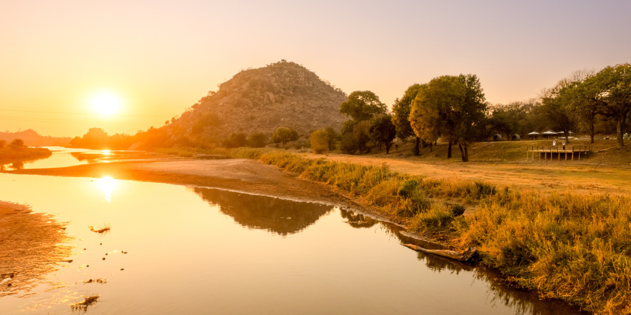 Olifants River in South Africa, with grassy banks and leafy hills in the background at sunset