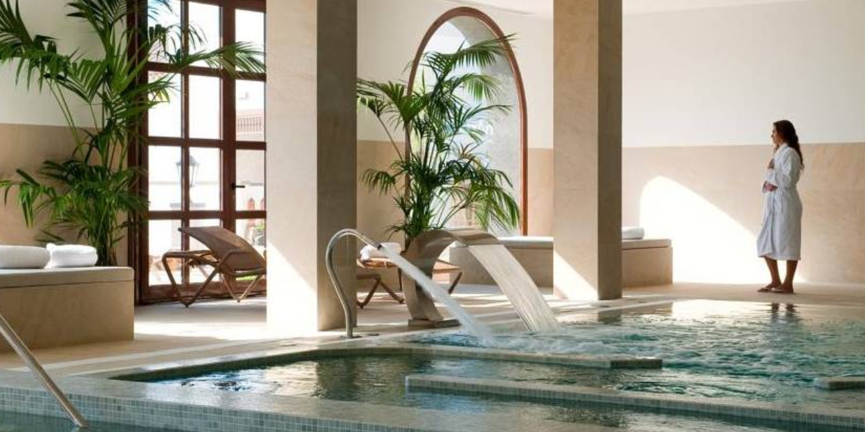 Woman in a white robe relaxing by the indoor pool at Hacienda del Conde spa, Tenerife