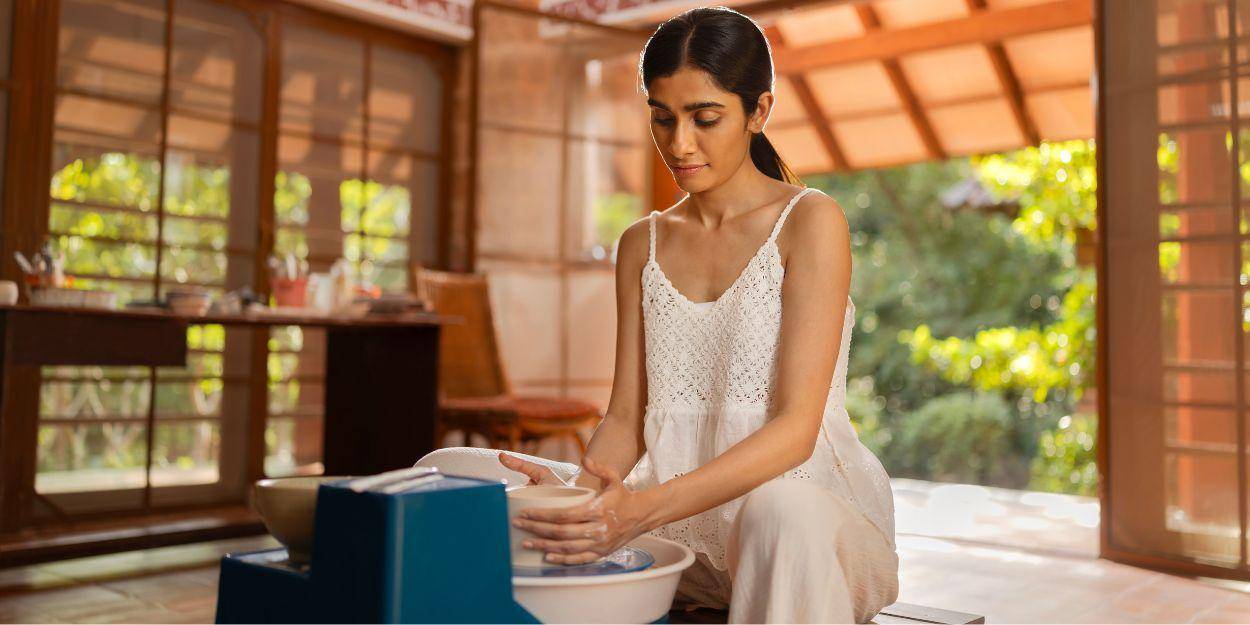 Woman in a white shirt working on a pottery at the studio
