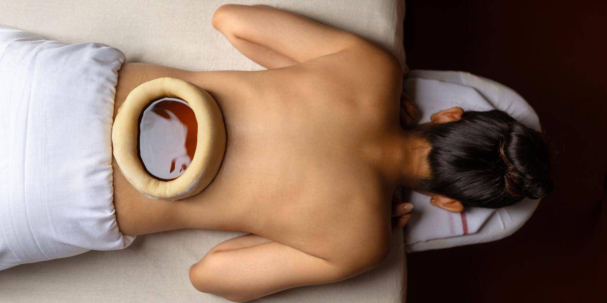 Woman on her front having a warm oil on her lower back