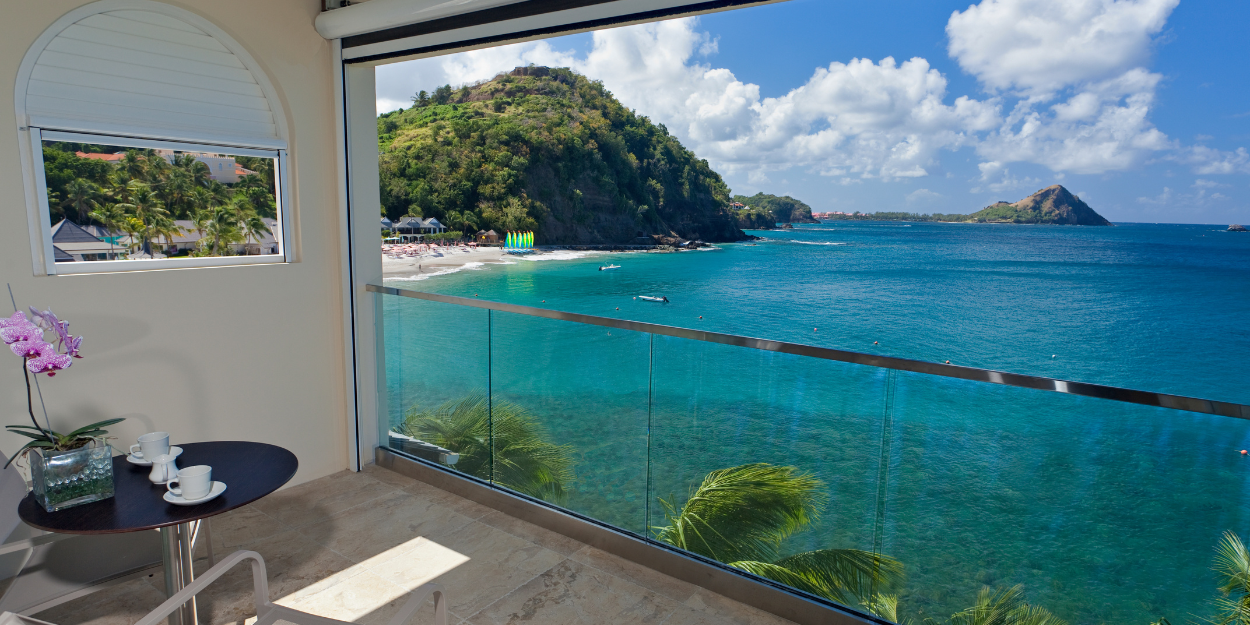 Ocean view room with a large window overlooking the sea and a comfortable bed.