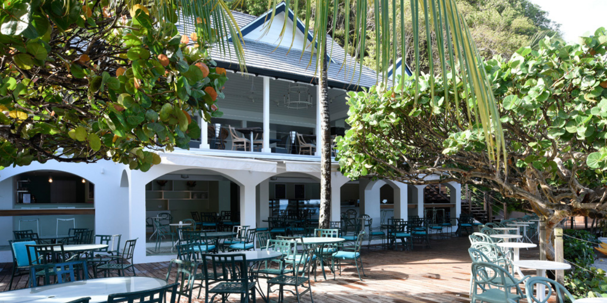 Elegant outdoor dining area set with tables and chairs surrounded by greenery.