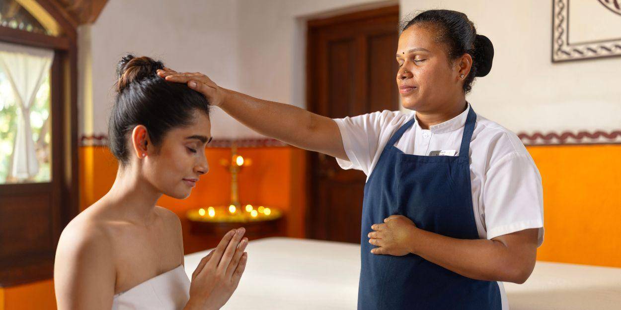 A therapist is preparing a guest for a treatment by blessing her