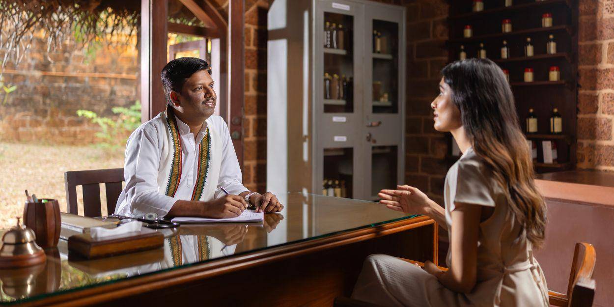 Guest having one on one consultation with resident Ayurvedic doctor in his office 