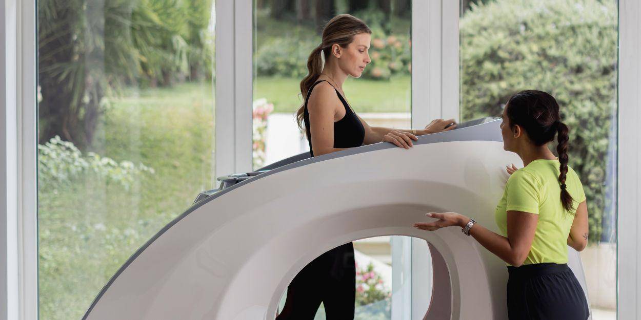 Female client with a private trainer using high-tech machine in the gym