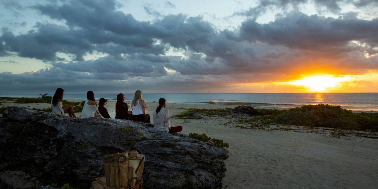 Reflective moments at Palmaïa – The House of AïA Group sitting on rocks on the beachfront, watching the sun rise or set above the ocean
