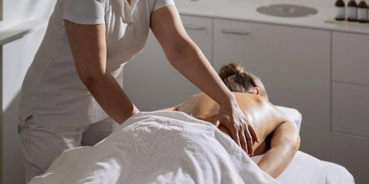 Female guest having a relaxing upper back massage in a treatment room with natural daylight 