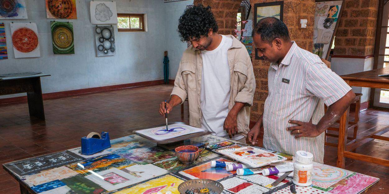 Male guests doing a painting at the studio and supervised by the member of the arts team