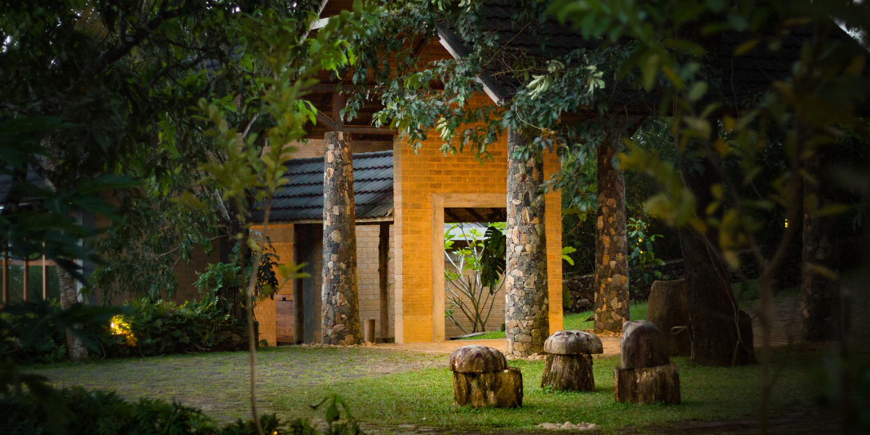 Yellow-painted building shrouded in greenery with sculptures out the front
