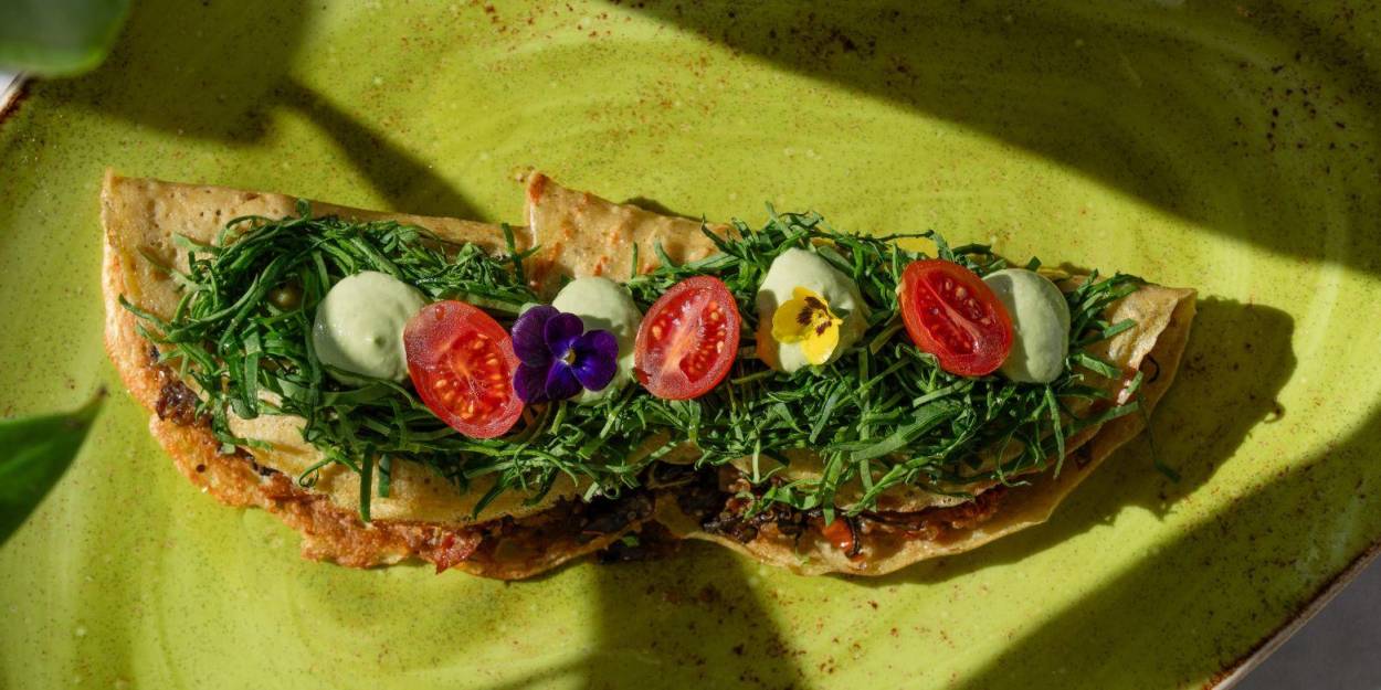 Inventive food at Palmaïa – The House of AïA Crispy tacos folded over and topped with greens, tomatoes and edible pansies