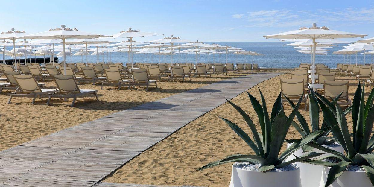 Wooden walkway on a beach furnished with loungers and parasols 