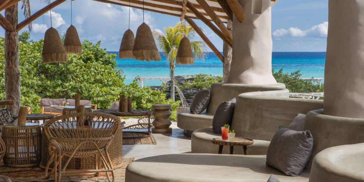 Al fresco seating areas at Palmaïa – The House of AïA Bohemian seating area with rattan lanterns and chairs, circular cushioned seating and a view of the ocean
