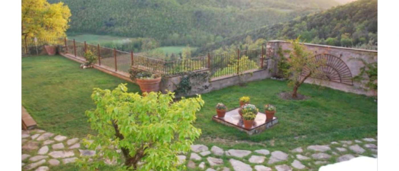 Grassy courtyard with railings and a cobbled stone path overlooking green hills