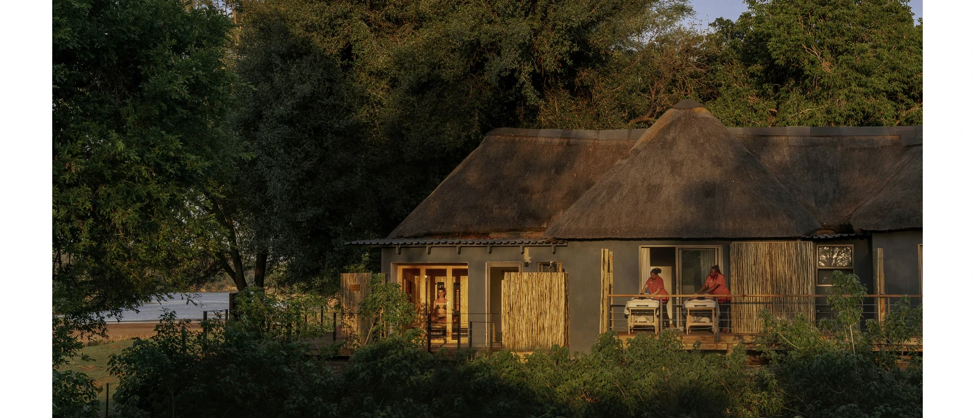 Wooden hut-style buildings showcasing open-air spa treatment rooms surrounded by greenery
