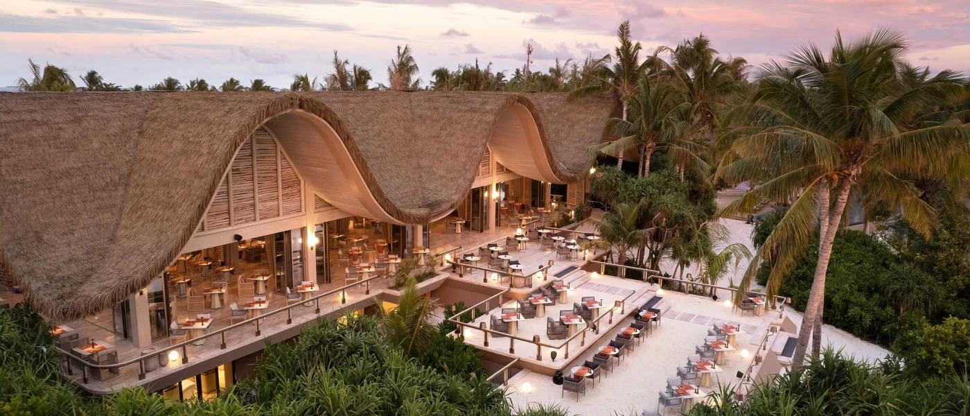 Thatched, curved roof restaurant, with multiple terraces including those right on the beach
