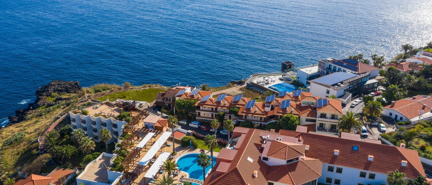 Sentido Galosol from above, including its oceanfront location, swimming pool, palm trees and terracotta-roofed buildings