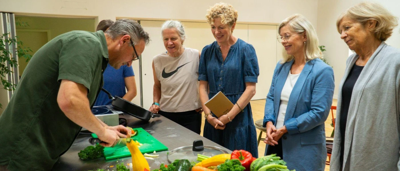 Group of women watching a chef prepare ingredients in a kitchen workshop