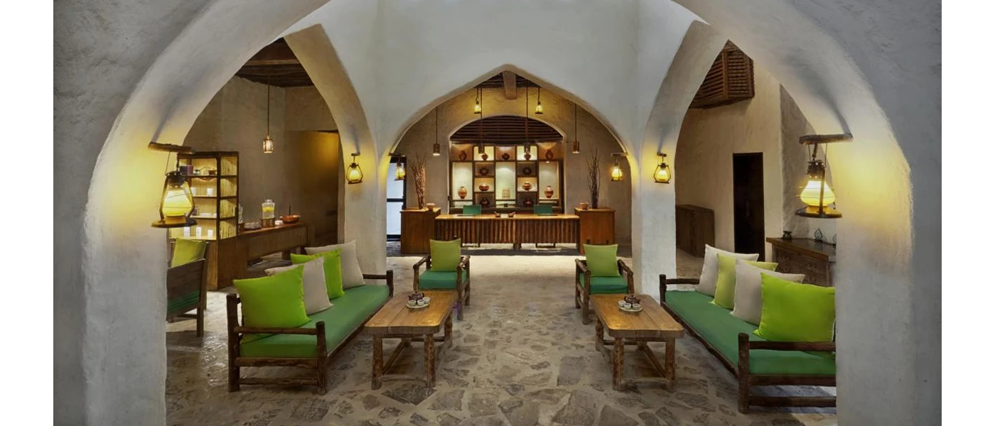 Hotel area with lime green sofas, stone floors, vaulted ceiling and atmospheric lighting