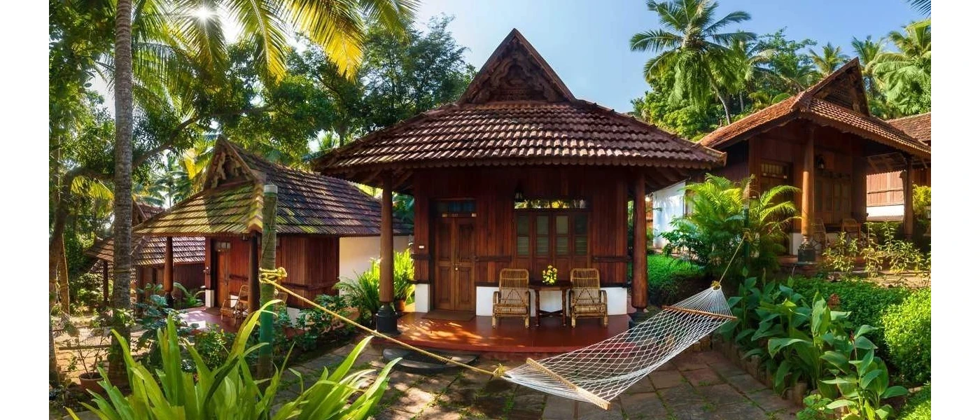 Little wooden huts with tiled rooftops and wooden terraces with a hammock in front, surrounded by tropical gardens