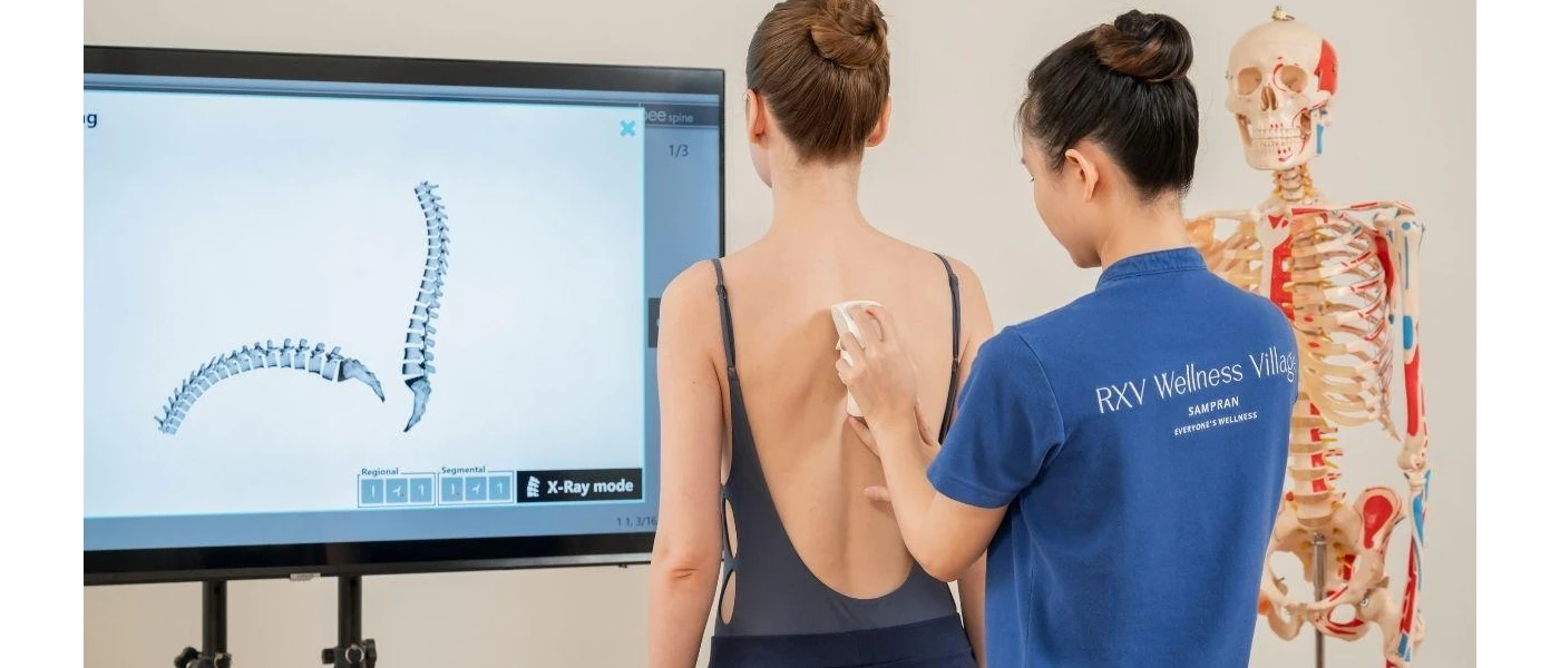 A therapist scans a woman's spine as she looks on at a screen showing it