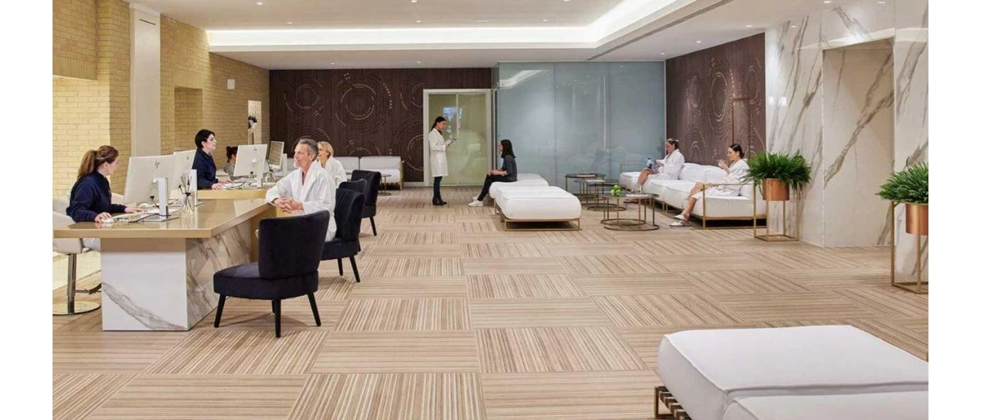 Room of people in white robes - some sitting at desks talking to health professionals, others relaxing while they wait to be seen