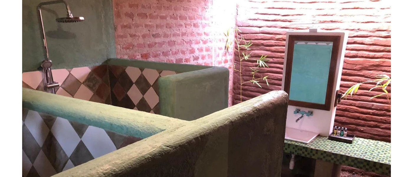 Open-ceiling bathroom with a walk-in tiled shower, stone walls and tiled vanity unit