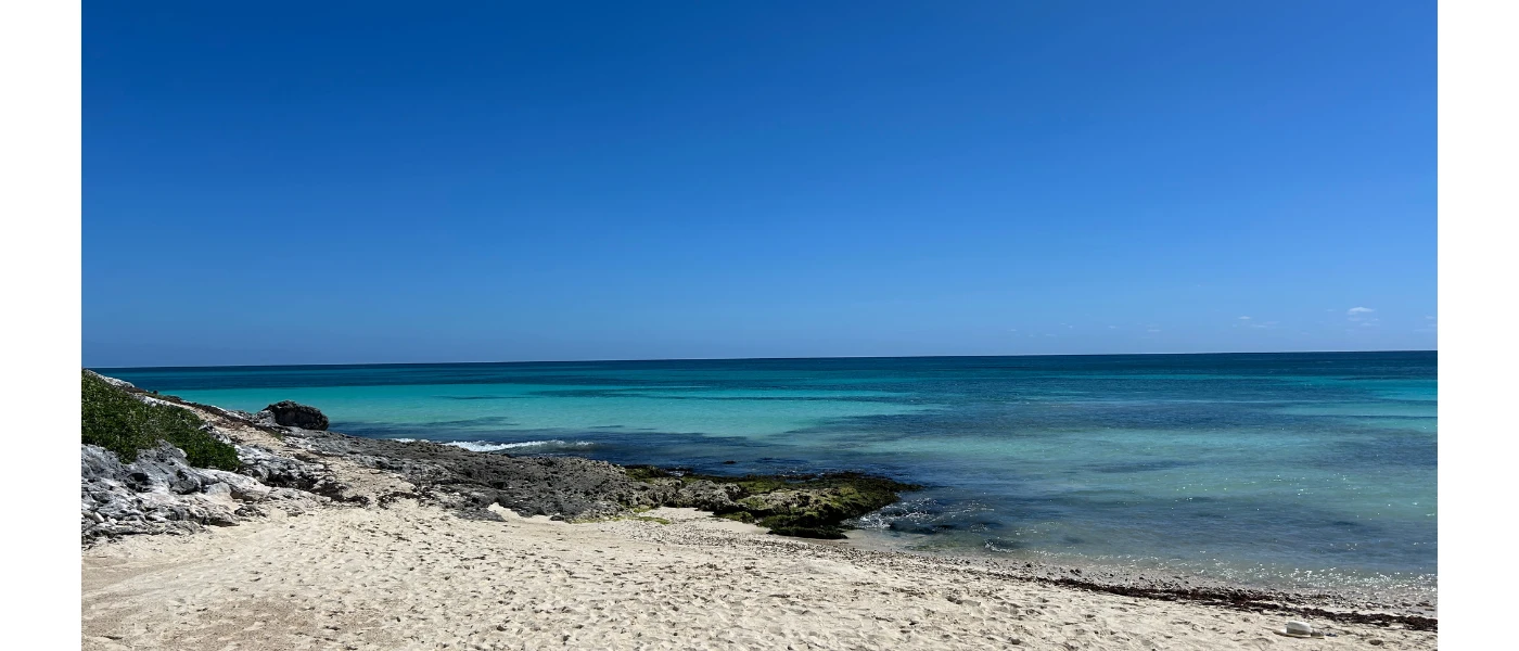 White sandy beach with turquoise shallows under a bright clear blue sky