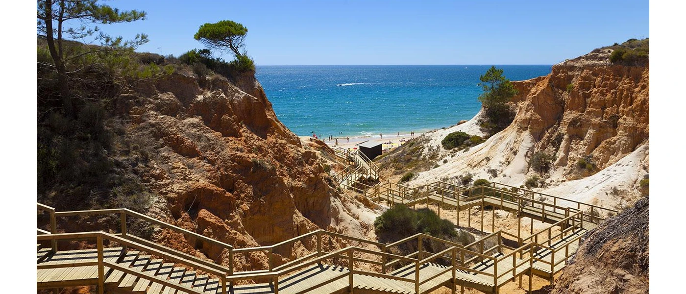 Wooden steps and walkway down to a golden sandy beach, sandwiched by cliffs