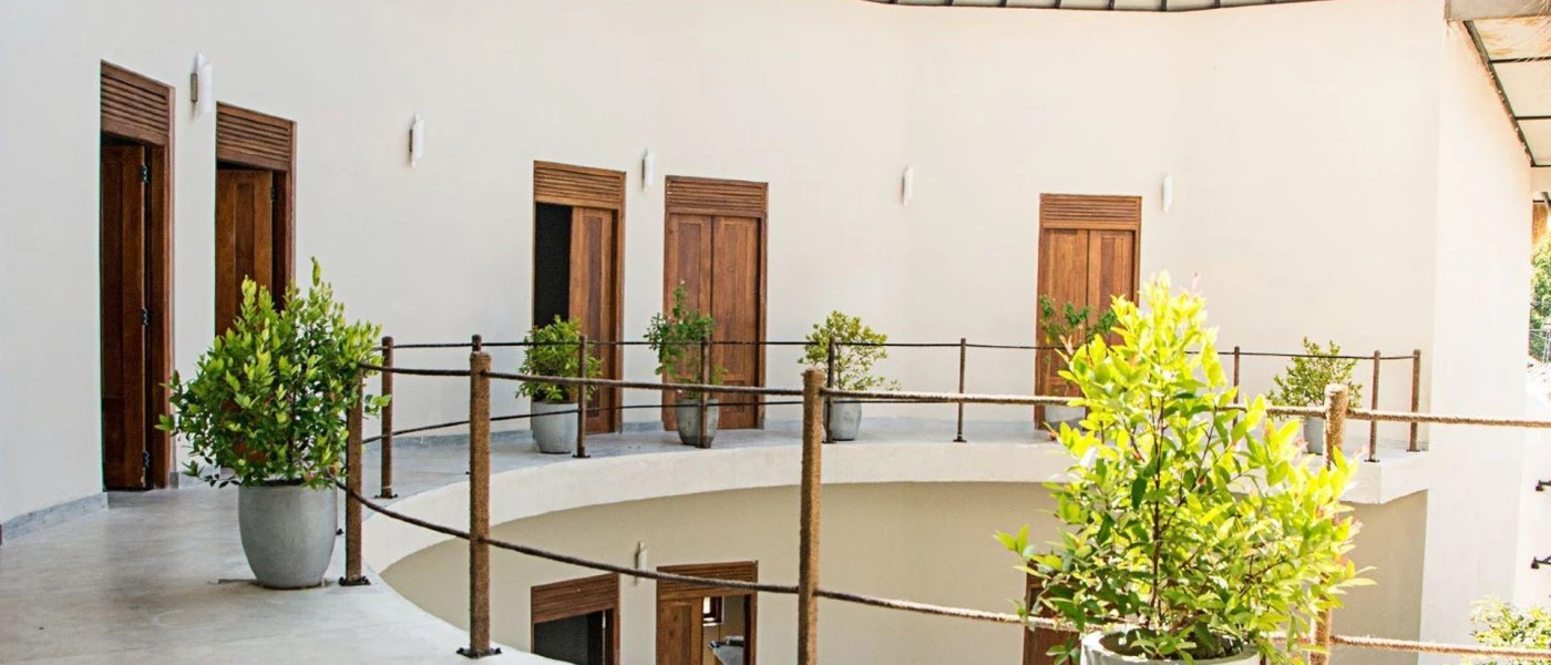 Two storeys in a white building with wooden doors and potted plants