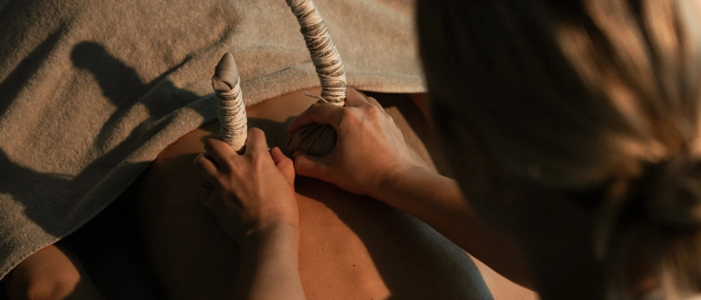 Therapist massages a guest on a bed lying on their front, with a towel covering their head