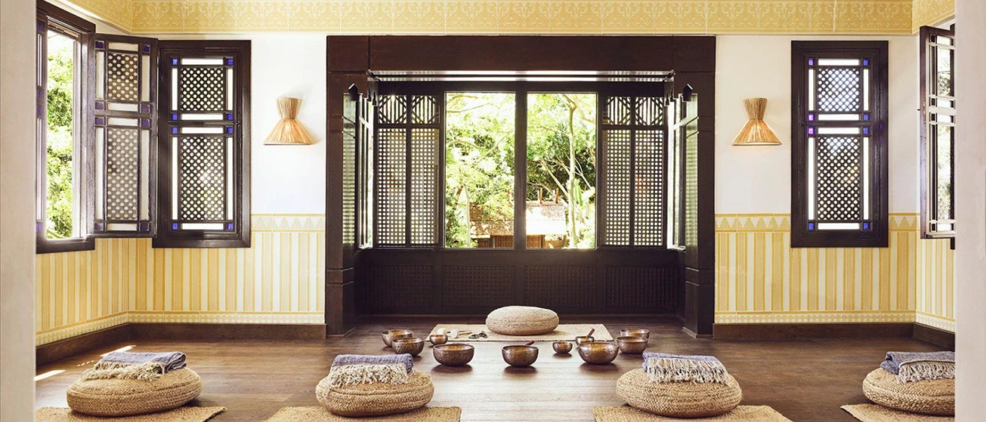 Wellness studio with rattan mats and cushions laid out for a class, with sound bowls laid out in a circle at the front