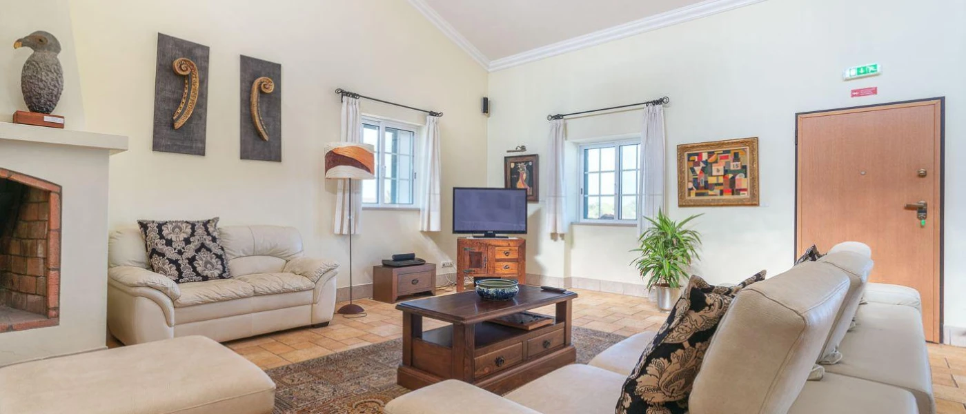 Neutral, cosy lounge with white sofas, a fireplace, framed pictures and a large wooden door