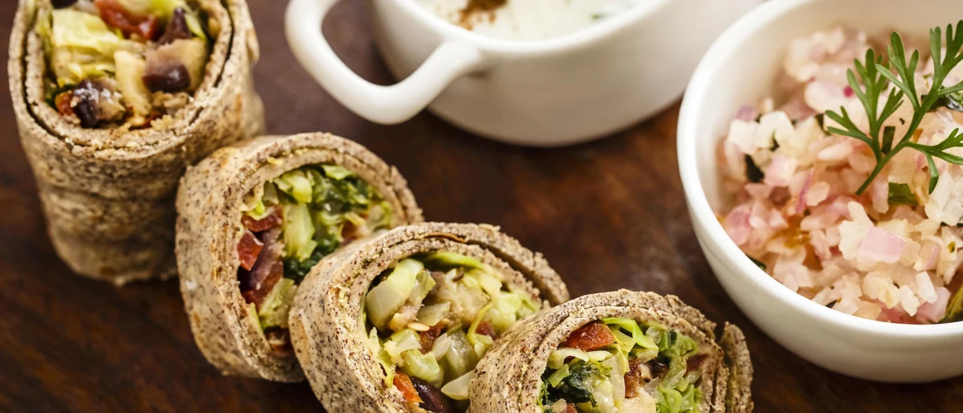 Wraps filled with colourful vegetables and a bowl of rice in close-up
