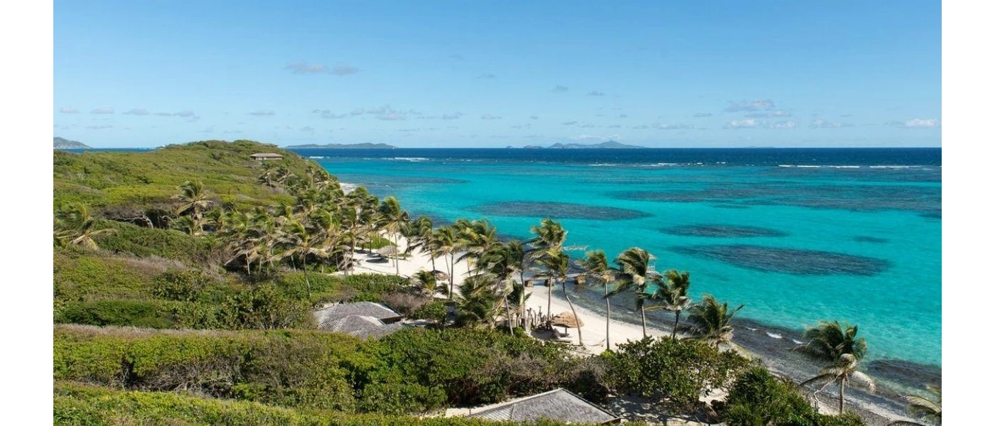 Tropical greenery, a white sandy beach, palm trees and turquoise waters of the ocean