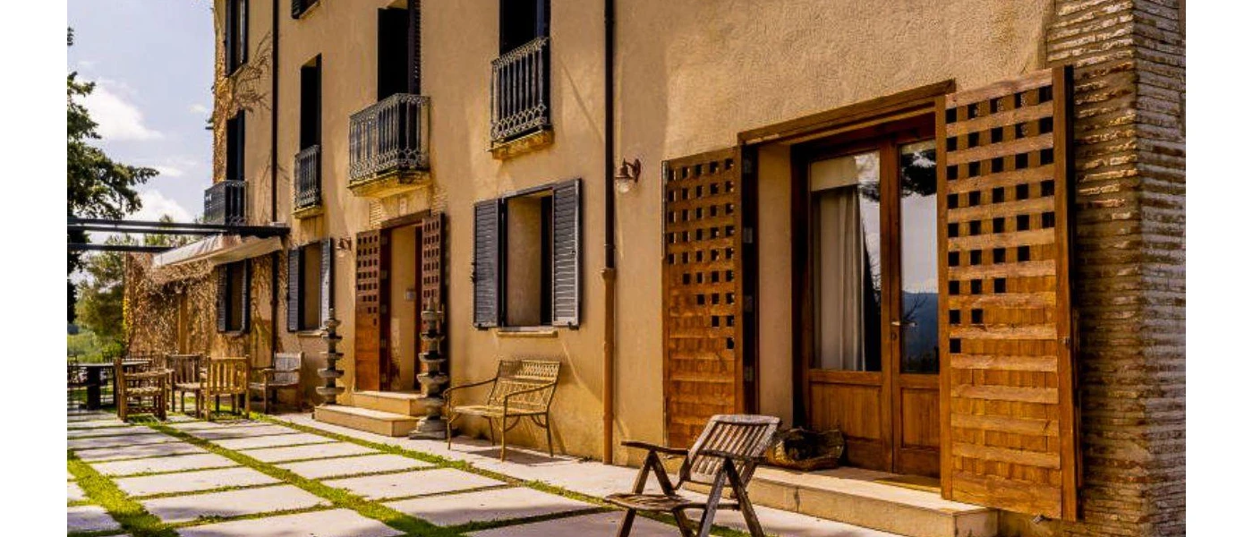 Rustic farmhouse exterior with cream walls and black wooden window shutters