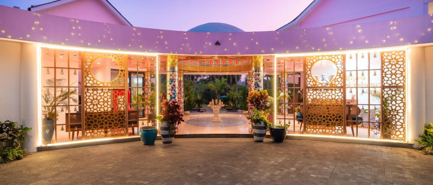 Hotel entrance with fairy lights, potted plants, and an intricately designed exterior with cut outs
