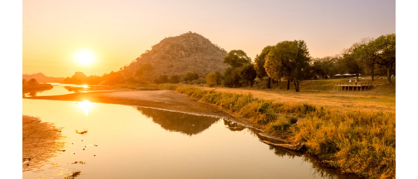Olifants River in South Africa, with grassy banks and leafy hills in the background at sunset