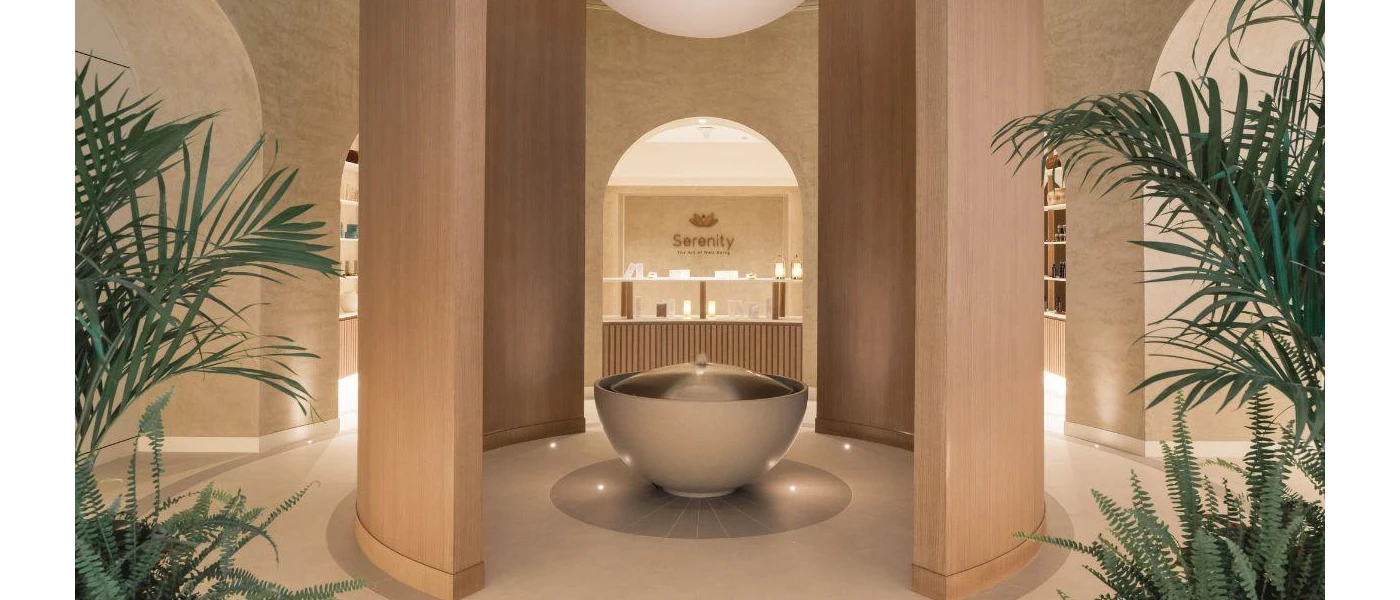 Archways, palm trees spotlighting and desk in a spa, with the words 'Serenity the art of wellbeing' etched on the wall