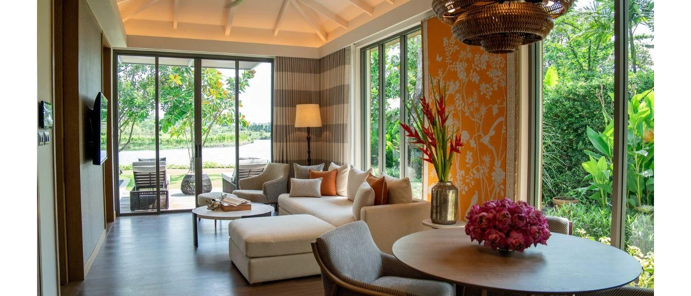 Villa interior with wooden flooring, yellow patterned wallpaper, beige sofas and a wall-hung TV