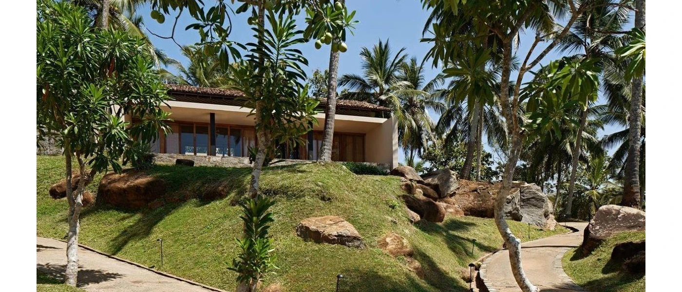Tiled-roof villa among grassy lawns, rockery and palm trees