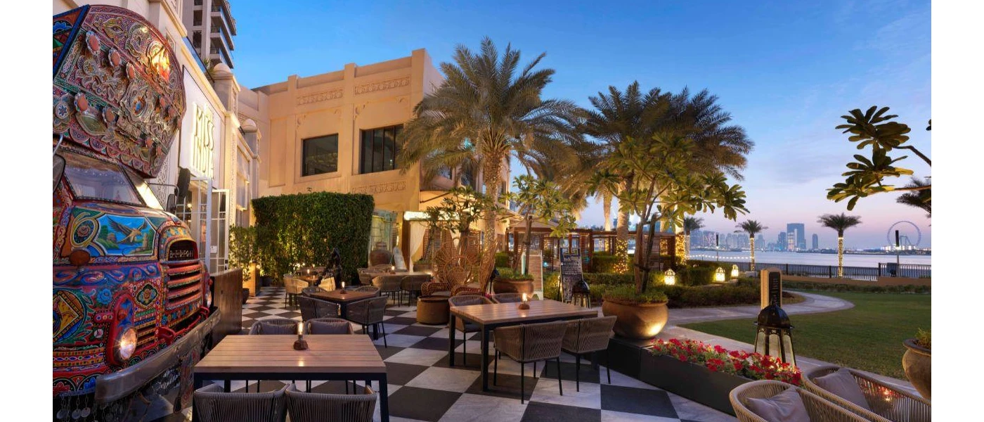 Outdoor terrace with seating and a sea view, an elegant black and white chequered floor and an intricately painted motor design