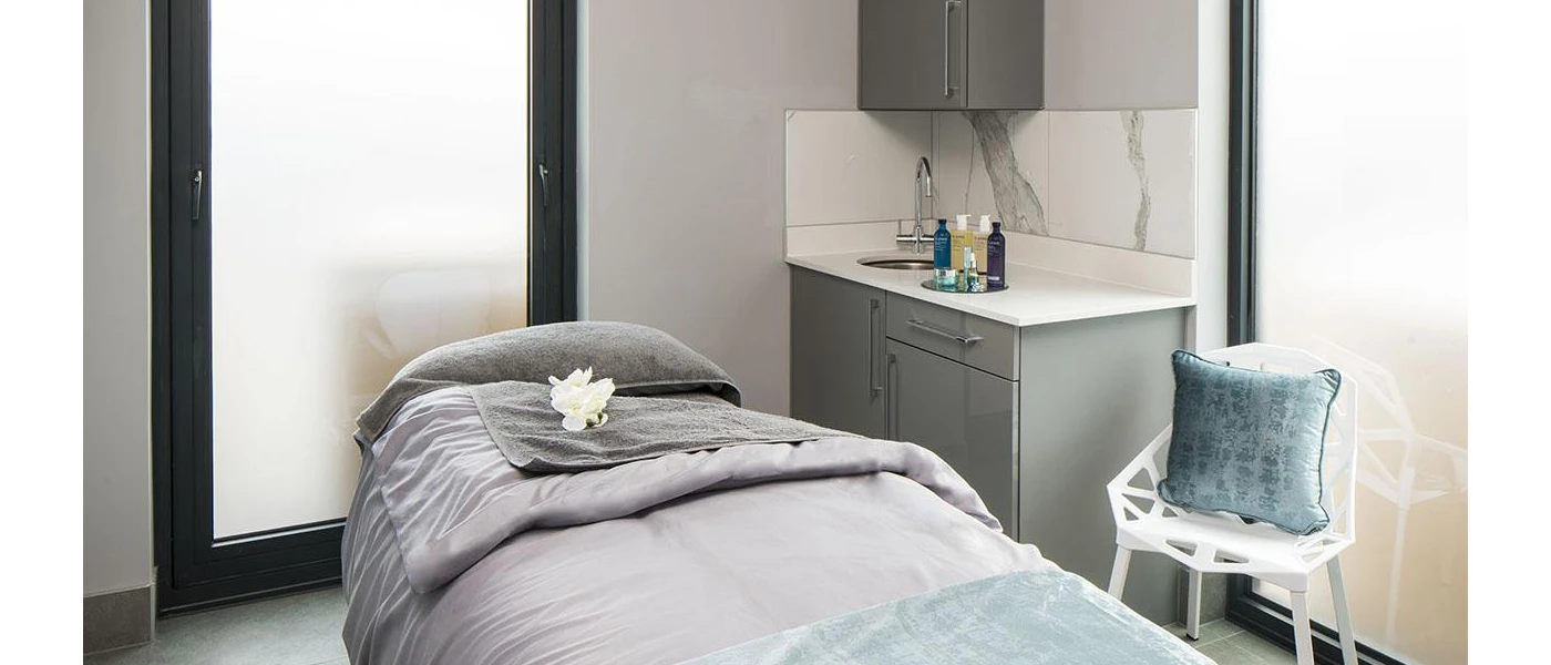 Spa treatment room with a bed, towel and grey furnishings